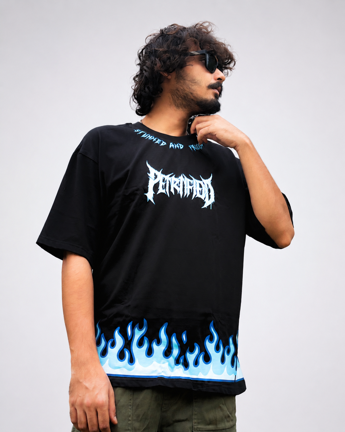 Front view of model wearing TNGS black oversized t-shirt with blue flame hem print and Petrified metal chest logo.