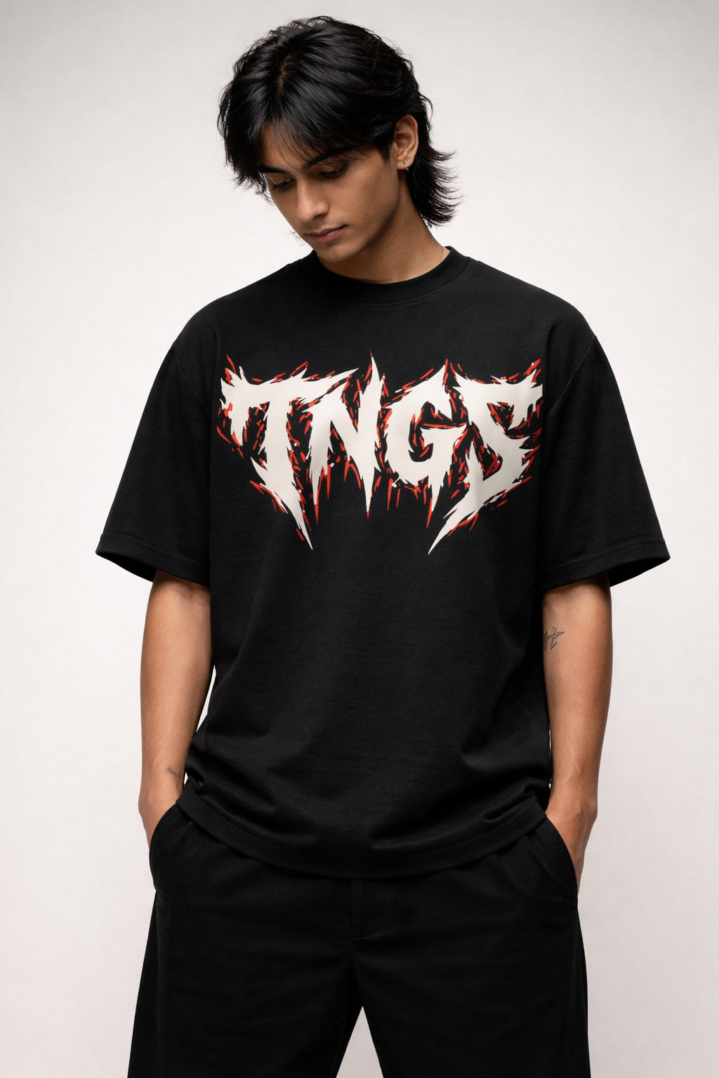 Front view of model wearing TNGS black oversized drop shoulder t-shirt with jagged white metal chest logo.