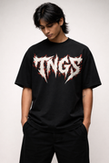 Front view of model wearing TNGS black oversized drop shoulder t-shirt with jagged white metal chest logo.