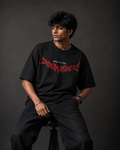Front view of model wearing TNGS black oversized t-shirt with crimson red Corrupt metal typography chest print.