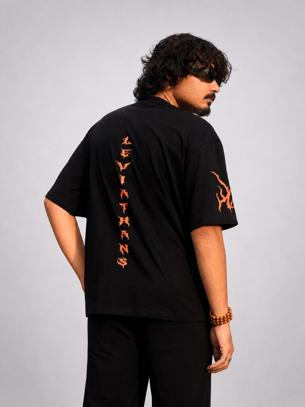 Back view of black streetwear tee featuring vertical orange Leviathans spine typography and sleeve tribal flame.

