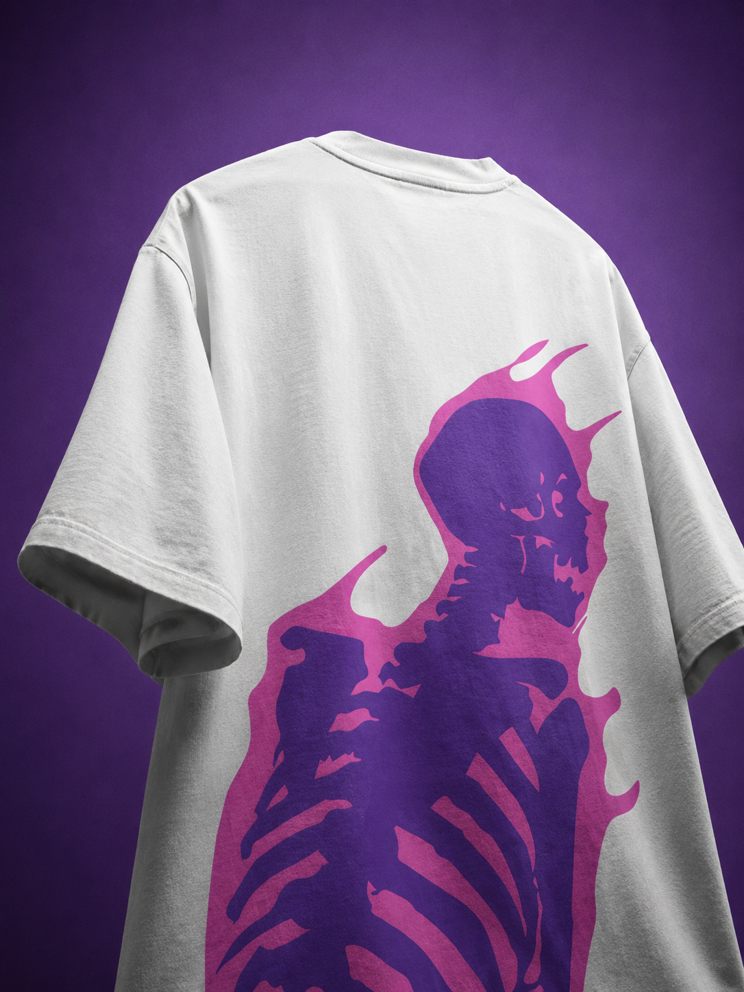 Back angle view of white oversized streetwear t-shirt featuring vibrant purple flaming skeleton skull graphic print.